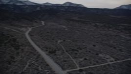 5K aerial stock footage of orbiting a desert road near mountains with light snow at twilight, Mojave Desert, California Aerial Stock Footage | AX0007_043