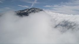 5K aerial stock footage approaching cloud cover near a frozen peak in the San Bernardino Mountains Aerial Stock Footage | AX0009_088E