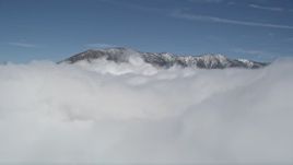 5K aerial stock footage orbit clouds to reveal snowy summits in San Bernardino Mountains in winter, California Aerial Stock Footage | AX0009_105