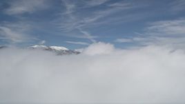 5K aerial stock footage of snowy San Bernardino Mountains beyond thick clouds in winter, California Aerial Stock Footage | AX0009_106