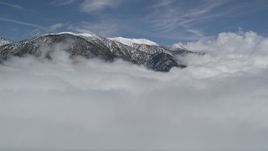 5K aerial stock footage approach snowy San Bernardino Mountains and fly over clouds in winter, California Aerial Stock Footage | AX0009_110E