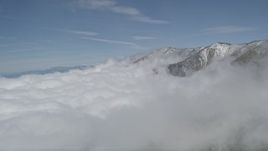 5K aerial stock footage flyby clouds to reveal San Bernardino Mountains with winter snow, California Aerial Stock Footage | AX0009_116