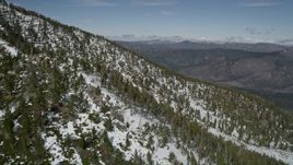 5K aerial stock footage fly over a frozen mountain slope to reveal evergreen forest valley, San Bernardino Mountains, California Aerial Stock Footage | AX0009_123