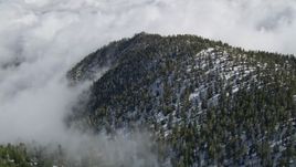 5K aerial stock footage orbit clouds surrounding mountains with snow in the San Jacinto Mountains, California Aerial Stock Footage | AX0010_071