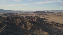 5K aerial stock footage fly by mountains revealing desert plain, Mojave Desert, California Aerial Stock Footage | AX0011_070
