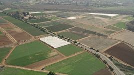 5K aerial  video of farmland and greenhouses beside a country road, Oceanside, California Aerial Stock Footage | AX0015_044
