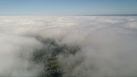 5K aerial stock footage of flying over a small break in thick cloud cover beneath blue skies, California Aerial Stock Footage | AX0015_051