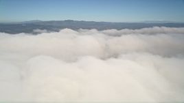 5K aerial stock footage of passing a thick cover of clouds below blue skies, California Aerial Stock Footage | AX0015_054