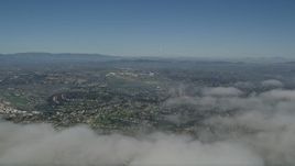 5K aerial stock footage pan across cloud cover to reveal suburban neighborhoods in Oceanside, California Aerial Stock Footage | AX0016_007