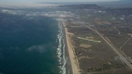 5K aerial stock footage of following an empty beach to approach small military airfield, Mcolf Camp Pendleton, California Aerial Stock Footage | AX0016_026