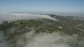 5K aerial stock footage follow the edge of the clouds to approach hillside homes, Laguna Niguel, California Aerial Stock Footage | AX0016_054E