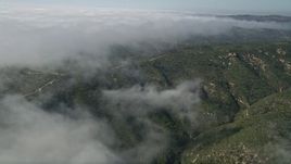 5K aerial stock footage approach a dirt road atop hills near the edge of rolling fog, Laguna Beach, California Aerial Stock Footage | AX0016_062