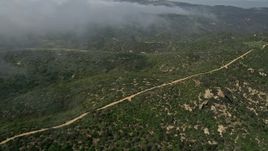 5K aerial stock footage fly over and pan across a dirt road on a hill near rolling fog, Laguna Beach, California Aerial Stock Footage | AX0016_063