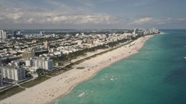 5K aerial stock footage tilt from sunbathers on the beach to a wider view of South Beach, Florida Aerial Stock Footage | AX0020_044