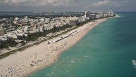 5K aerial stock footage tilt from beachgoers and sunbathers to beachfront buildings in South Beach, Florida Aerial Stock Footage | AX0020_045