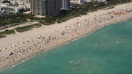 5K aerial stock footage of large group of sunbathers and beachgoers by the ocean in South Beach, Florida Aerial Stock Footage | AX0020_047