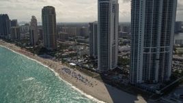 5K aerial stock footage approach beachfront luxury resort hotel and tilt to sunbathers on the beach in Sunny Isles Beach, Florida Aerial Stock Footage | AX0020_082E