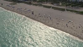 5K aerial stock footage tilt down to people enjoying the beach by condos in South Beach, Florida Aerial Stock Footage | AX0021_056E