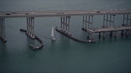 5K aerial stock footage of sailing boat under a bridge on the Rickenbacker Causeway at sunset in Florida Aerial Stock Footage | AX0022_073E