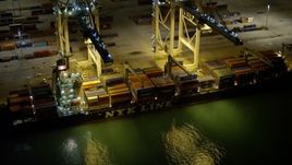 5K aerial stock footage of two cranes loading a cargo ship at night at the Port of Miami, Florida Aerial Stock Footage | AX0023_062E