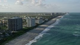 5K aerial stock footage of following the beach by apartment buildings, Juno Beach, Florida Aerial Stock Footage | AX0032_129