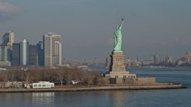 5K aerial stock footage orbit the torch side of the Statue of Liberty, New York, reveal Lower Manhattan skyline in the background, winter Aerial Stock Footage | AX0065_0078E