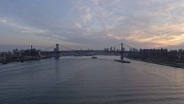 5K aerial stock footage follow the East River to approach barges near the Williamsburg Bridge, New York City, winter, sunset Aerial Stock Footage | AX0065_0170