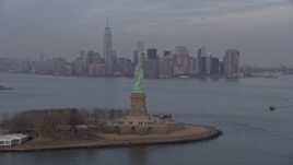 5K aerial stock footage pass by the Statue of Liberty monument on Liberty Island with Lower Manhattan skyline in the background in New York, winter, twilight Aerial Stock Footage | AX0065_0187E