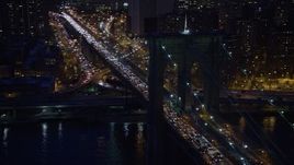 5K aerial stock footage track an arch in the Brooklyn Bridge with heavy traffic, Lower Manhattan, New York City, winter, night Aerial Stock Footage | AX0065_0282