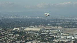 7.6K aerial stock footage of the Goodyear Blimp approaching the airport, Downtown LA skyline in background, Long Beach, California Aerial Stock Footage | AX0160_061