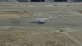 7.6K aerial stock footage of a private jet taxiing down a runway at Long Beach Airport, California Aerial Stock Footage | AX0160_068