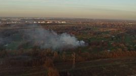 4K aerial stock footage of a fire in the trees at a golf course at sunset in Lockport, Illinois Aerial Stock Footage | AX0163_0004