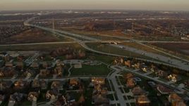 4K aerial stock footage fly over suburban homes and pass light freeway traffic at sunset in Lemont, Illinois Aerial Stock Footage | AX0163_0005