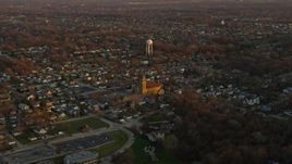 4K aerial stock footage of passing suburban homes and church near water tower at sunset in Lemont, Illinois Aerial Stock Footage | AX0163_0006