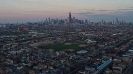 4K aerial stock footage of tilting from an urban West Side neighborhood to reveal the Chicago skyline at sunset, Illinois Aerial Stock Footage | AX0163_0023