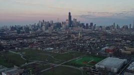 4K aerial stock footage of tilting from an urban West Side neighborhood and railroad tracks to reveal the Chicago skyline at sunset, Illinois Aerial Stock Footage | AX0163_0024