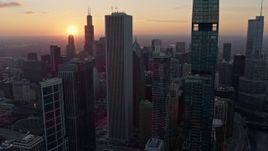 4K aerial stock footage of flying by Downtown Chicago skyscrapers with a view of the setting sun, Illinois Aerial Stock Footage | AX0170_0018