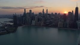 4K aerial stock footage of flying by the downtown skyline with setting sun in the distance, Downtown Chicago, Illinois Aerial Stock Footage | AX0170_0022