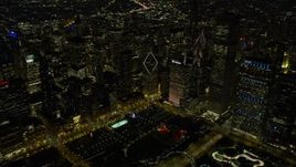 4K aerial stock footage fly over Grant Park nearby skyscrapers, some with holiday lights at night, Downtown Chicago, Illinois Aerial Stock Footage | AX0170_0080