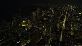 4K aerial stock footage fly over downtown skyscrapers, some with holiday lights, toward Grant Park at night, Downtown Chicago, Illinois Aerial Stock Footage | AX0170_0084