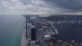 6.7K aerial stock footage tilt from the ocean to reveal condo complexes in Sunny Isles Beach, Florida and distant Miami skyline Aerial Stock Footage | AX0172_073