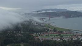 6K aerial stock footage the Golden Gate Bridge seen from a fog bank over The Presidio, California Aerial Stock Footage | AX0173_0095