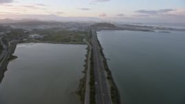 6K aerial stock footage tilt from Bayshore Fwy to reveal the distant San Francisco skyline at sunset, California Aerial Stock Footage | AX0174_0071