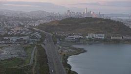 6K aerial stock footage tilt from freeway to reveal the distant San Francisco skyline at sunset, California Aerial Stock Footage | AX0174_0072