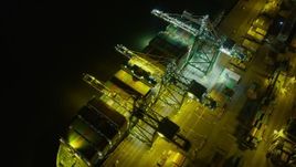 6K aerial stock footage passing by a cargo ship at the Port of Oakland at night, California Aerial Stock Footage | AX0174_0199