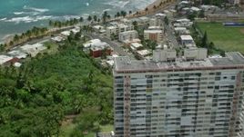 4.8K aerial stock footage fly over condos and beachfront property, tilt to reveal jungle by the beach, Luquillo, Puerto Rico Aerial Stock Footage | AX102_050E