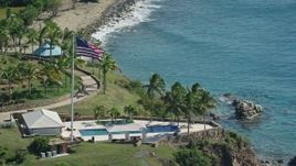 4.8K aerial stock footage of an Oceanfront pool and American flag along Caribbean blue waters, Little St James Island, St Thomas  Aerial Stock Footage | AX102_254