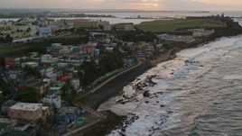 4.8K aerial stock footage of passing oceanfront homes near a cemetery on the way to fort and lighthouse, Old San Juan, Puerto Rico, sunset Aerial Stock Footage | AX104_078E