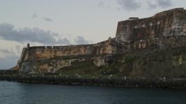 4.8K aerial stock footage flying along the walls of Fort San Felipe del Morro, Old San Juan, twilight Aerial Stock Footage | AX104_081E