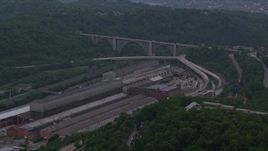 4K aerial stock footage approaching a factory and bridge surrounded by trees, East Pittsburgh, Pennsylvania Aerial Stock Footage | AX108_008E